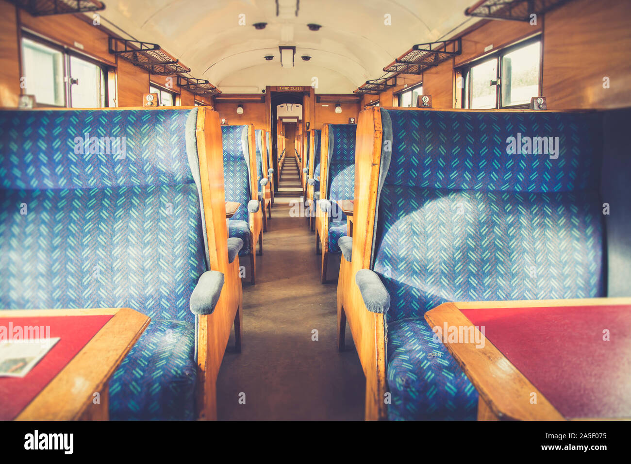 All'interno vuoto vintage UK carrozza ferroviaria. Interni sedili passeggero illuminato da autunno luminoso sole che splende attraverso il treno di windows. Patrimonio i treni a vapore NEL REGNO UNITO. Foto Stock