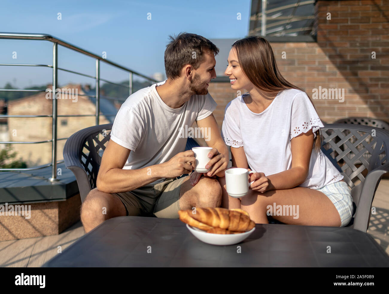 Coppia giovane ha un dolce parlare durante una colazione all'aperto su una terrazza Foto Stock