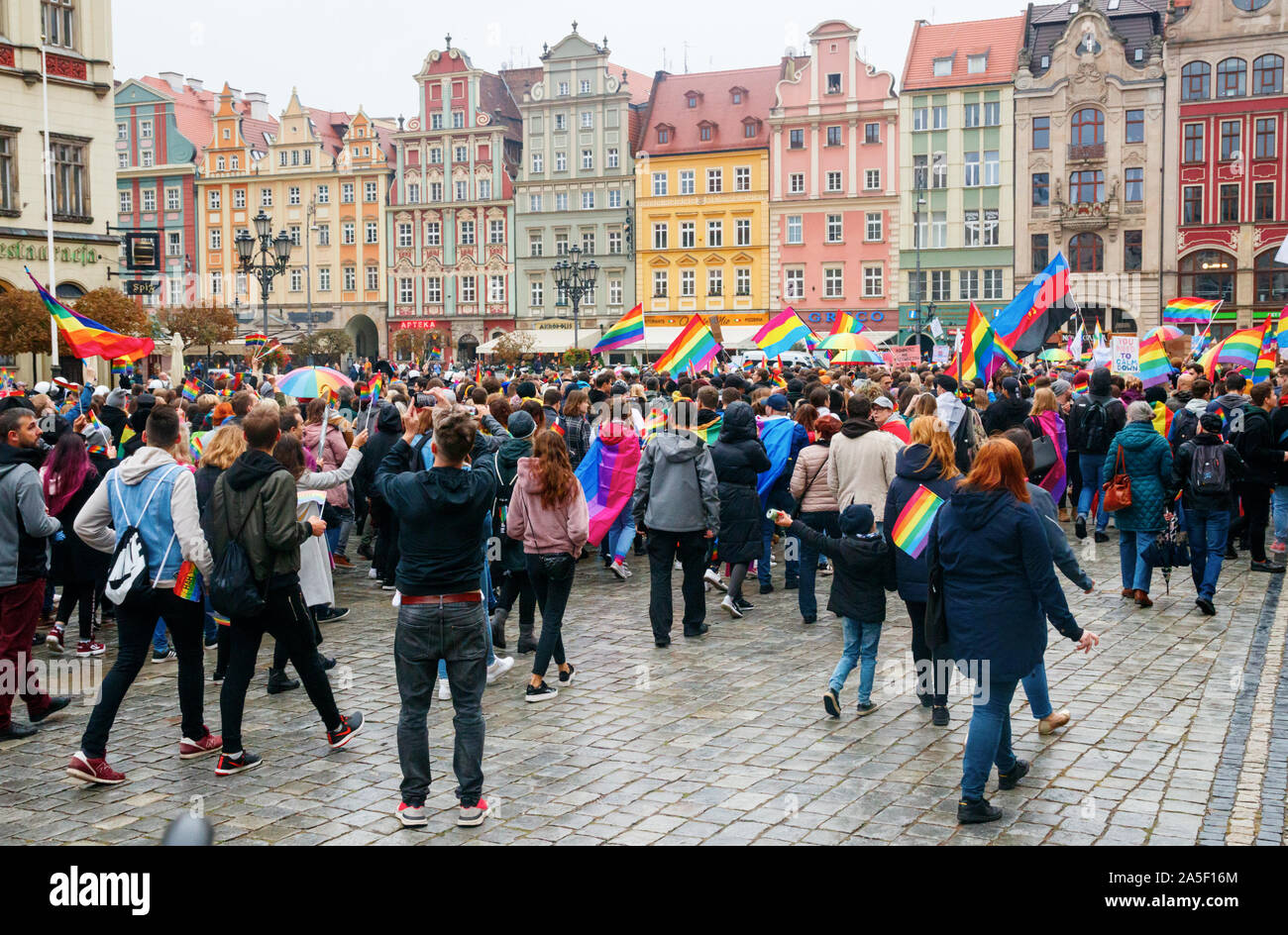 La folla con bandiere arcobaleno, partecipando in Wroclaw uguaglianza Marzo, promuovendo i diritti LGBT con vecchie case in background. Wroclaw, Polonia. Foto Stock