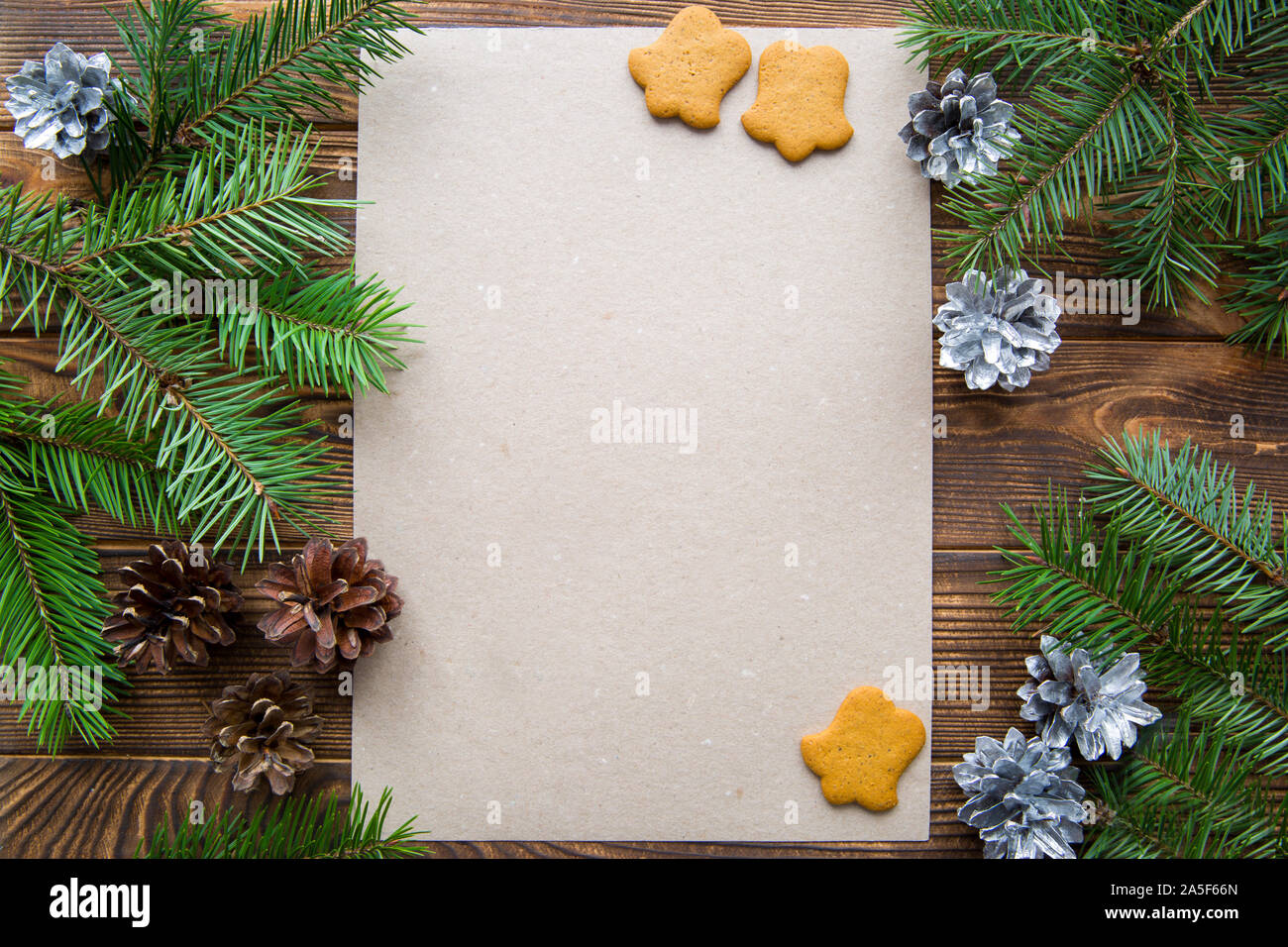 Abete rami di pino coni d'argento e pan di zenzero biscotti a forma di campana marrone sul tavolo di legno. Sfondo di natale. Spazio libero per il testo. Foto Stock