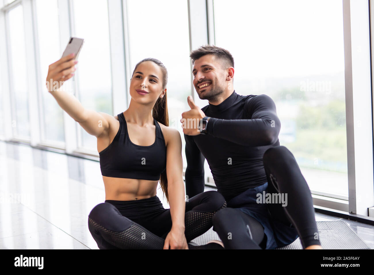 Coppia giovane rendendo selfie presso la palestra. Atleta uomo e donna prendendo foto sullo smartphone avente pausa dopo la formazione, spazio di copia Foto Stock