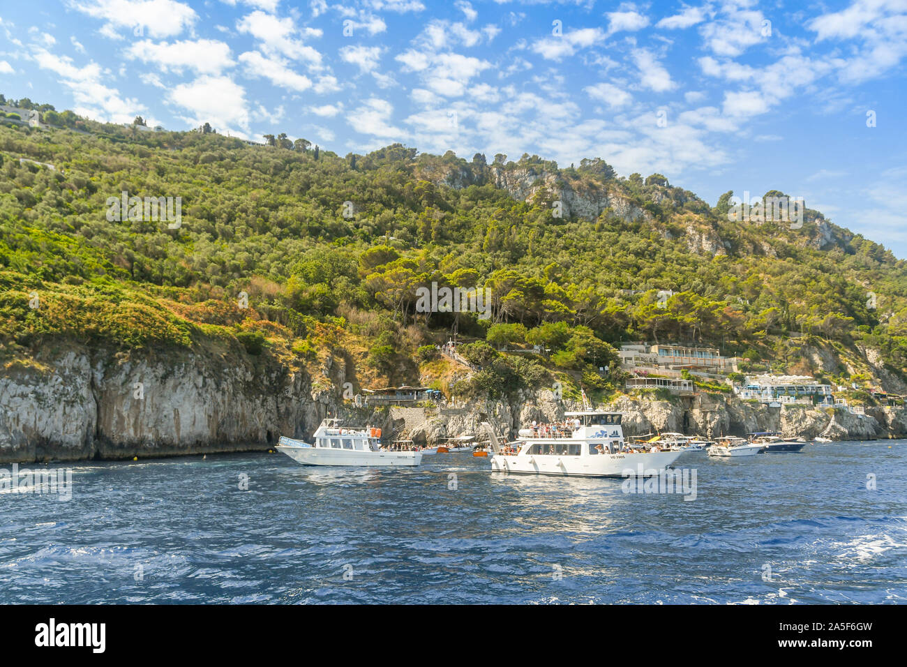 Isola di Capri - Agosto 2019: piccole imbarcazioni in attesa di visitare la "Grotta Azzurra" o "Grotta Azzurra" grotta sulla costa dell'isola di Capri Foto Stock