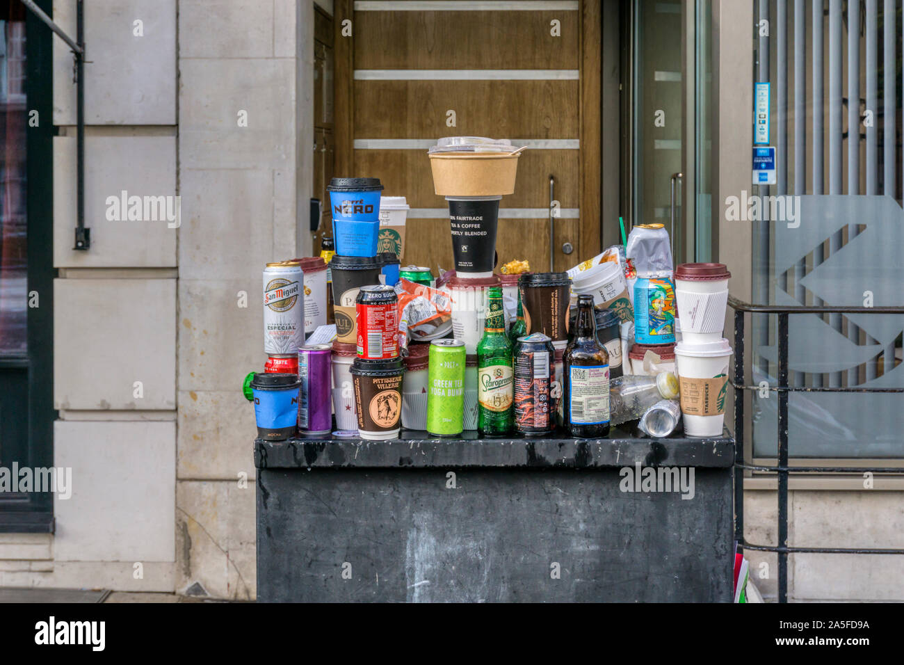 Spazzatura bilanciato su arredo urbano dopo la manifestazione di protesta nel centro di Londra. Takeaway tazze da caffè, lattine di birra e bottiglie e rapida di contenitori per alimenti. Foto Stock