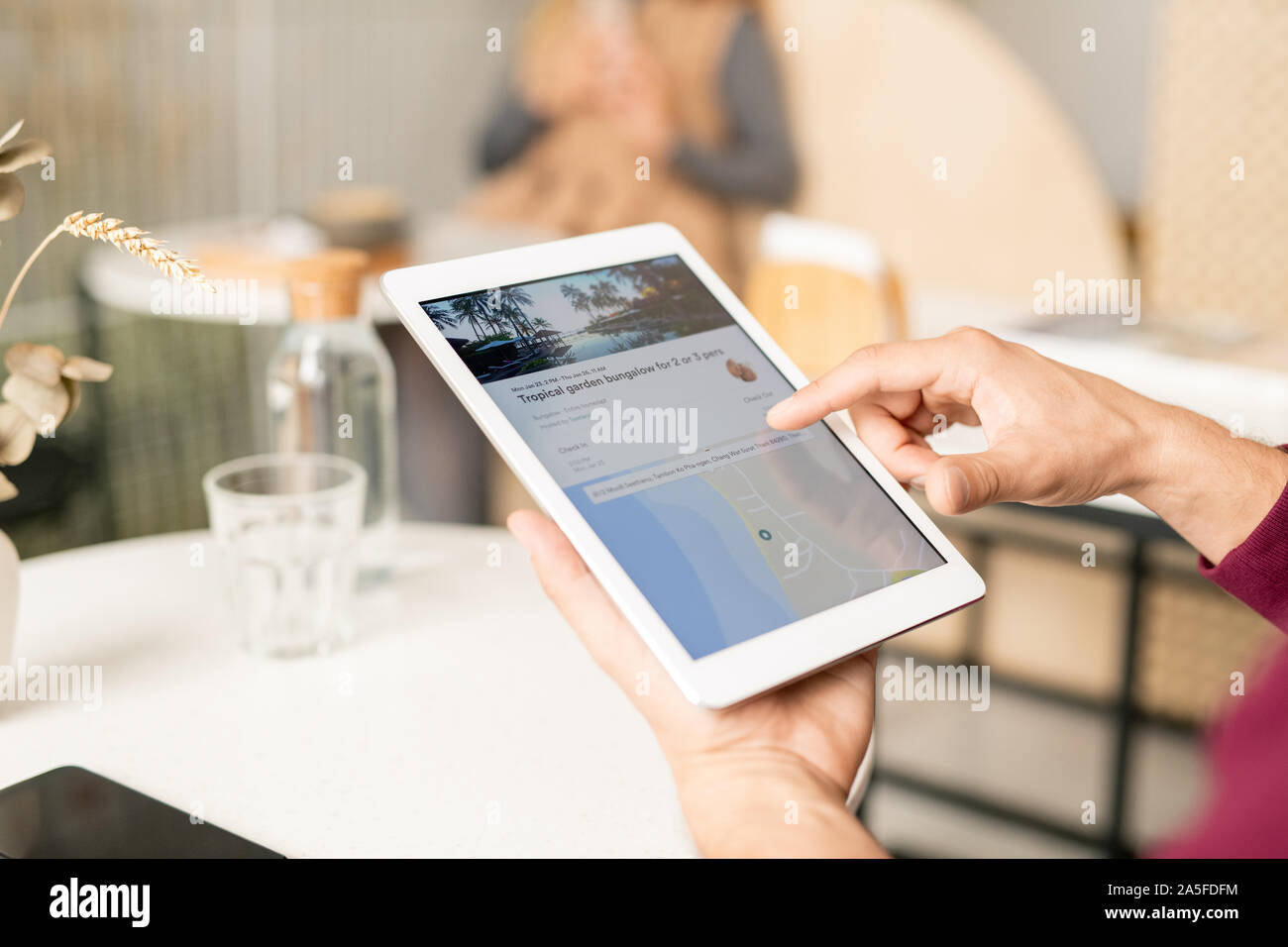 Mano maschio su tablet lo scorrimento dello schermo attraverso il sito web di viaggio mentre è in corso la ricerca di Nizza adatto luogo turistico Foto Stock