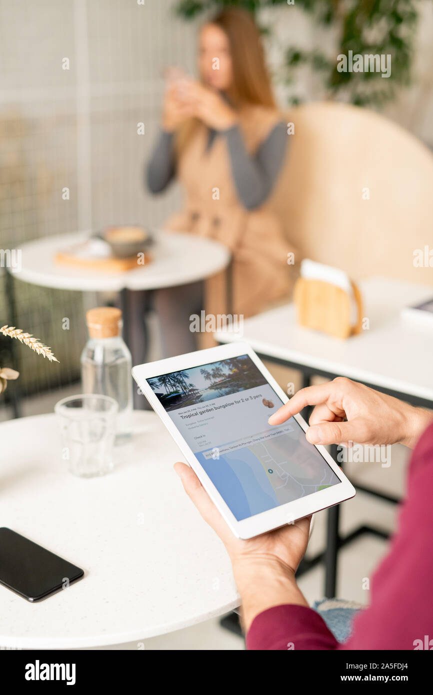 Mano umana oltre il touchpad rivolti a schermo durante la navigazione sul sito web per i turisti e alla ricerca di viaggio Foto Stock