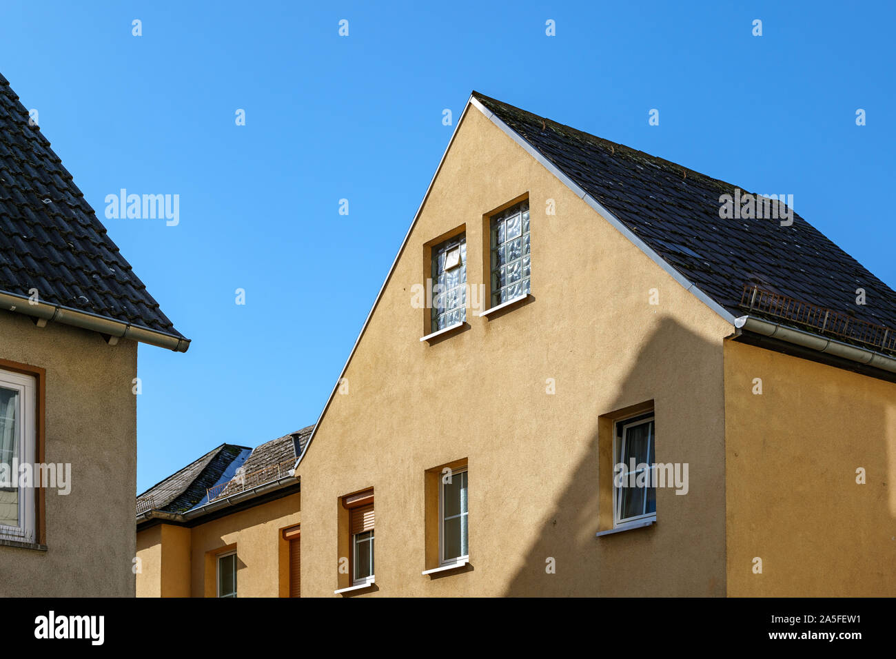 Veduta esterna del tipico edificio in stile moderno contemporaneo gamble tetto, semplici finestre rettangolari e giallo la facciata esterna, in Europa. Foto Stock