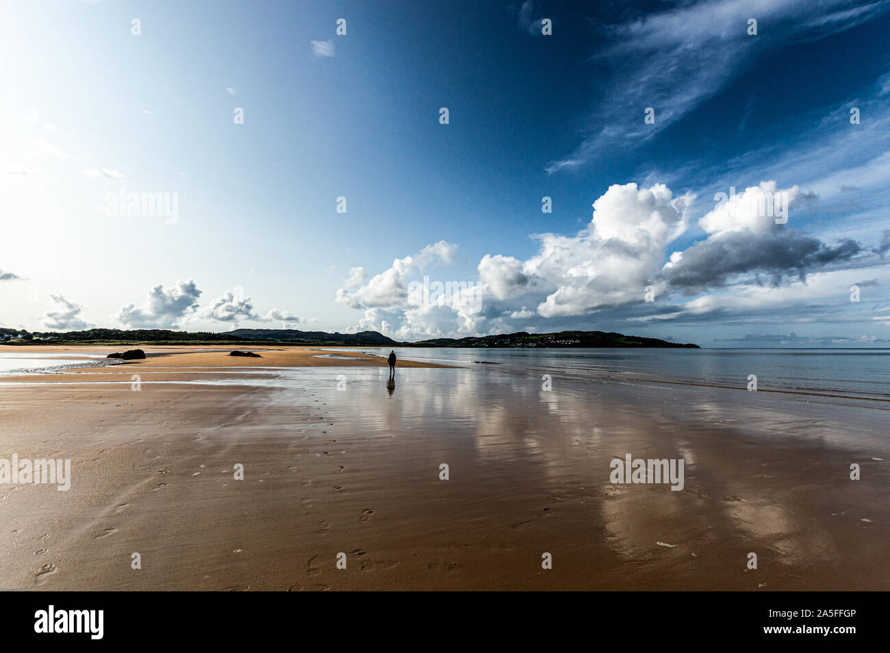 Un camminatore solitario riflesso con nuvole sul filamento Ballymastocker, Donegal, Irlanda Foto Stock