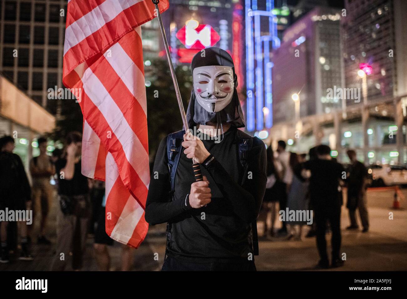 Un manifestante mascherato detiene una bandiera americana durante la dimostrazione.la gente di Hong Kong chiamata per International SOS e umanità aiuto al posto di Edimburgo, Centrale in una dimostrazione contro l'Anti-mask legge. Hong Kong è chief executive Carrie Lam invocato l uso dei regolamenti di emergenza ordinanza (ERO) consentendo al governo di vietare l'uso di maschere in pubbliche riunioni. Foto Stock