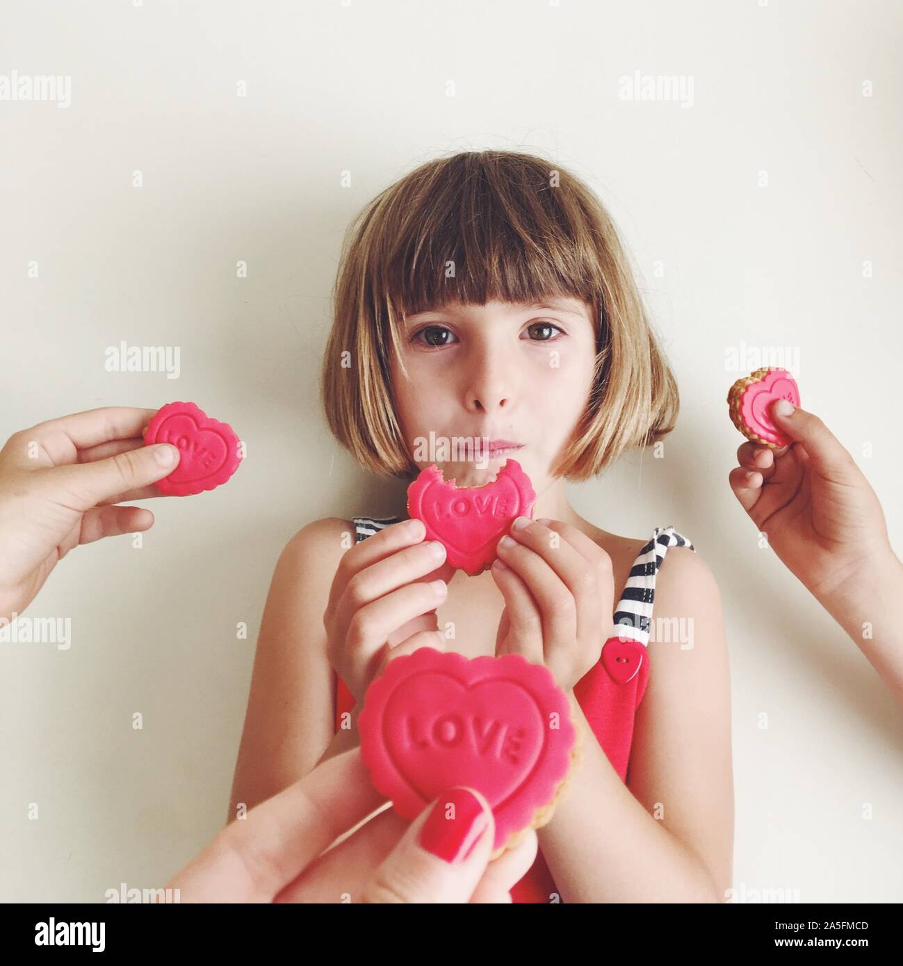 Ragazza di mangiare un amore cookie e persone offrendo la sua più cookie Foto Stock