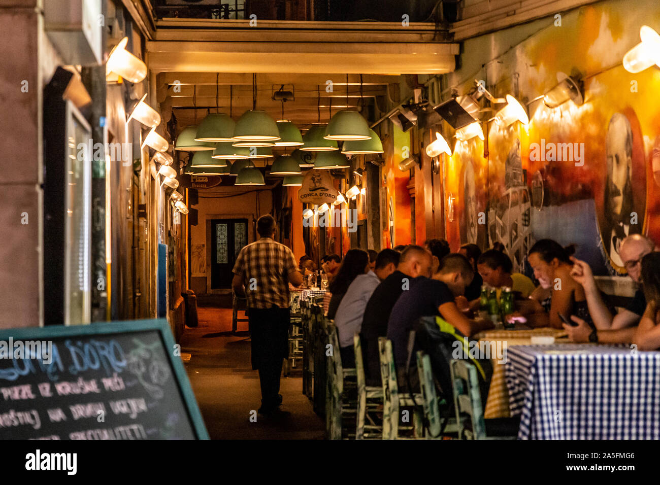 Persone dining & socializzazione all'aperto su una calda serata estiva in Pizza Bracera ristorante appena fuori il Korzo strada dello shopping di Rijeka, Croazia Foto Stock
