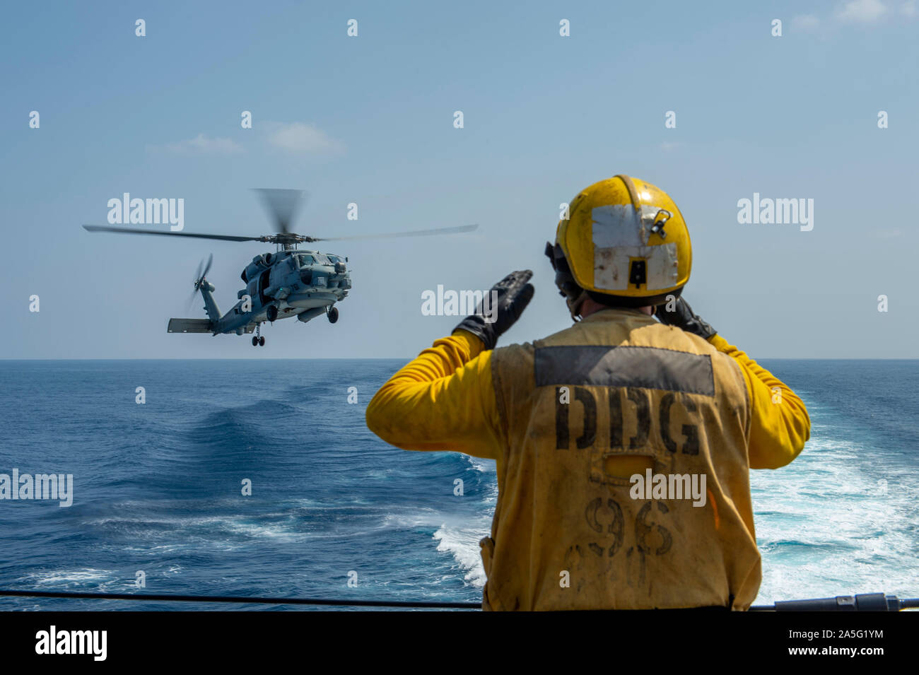 191017-N-SS350-1061 MAR ROSSO (ott. 17, 2019) di Boatswain Mate 2a classe Craig Smitherman dirige un MH-60R Sea Hawk elicottero, assegnato al "Granmaestro" di elicottero Maritime Strike Squadron (HSM) 46, durante un rifornimento verticale della formazione a bordo guidato-missile destroyer USS Bainbridge (DDG 96). Bainbridge è distribuito negli Stati Uniti Quinta Flotta area di operazioni a sostegno di operazioni navali per garantire stabilità marittimo e la sicurezza nella regione centrale, collegando i paesi del Mediterraneo e del Pacifico attraverso l'Oceano Indiano occidentale e tre strategici punti di strozzatura. (U.S. Navy photo by Mas Foto Stock