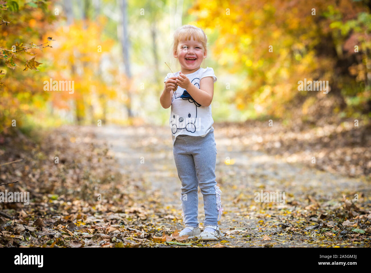 Felice piccolo bambino, Baby girl ridendo e giocando in autunno la natura a piedi all'aperto nella foresta Foto Stock