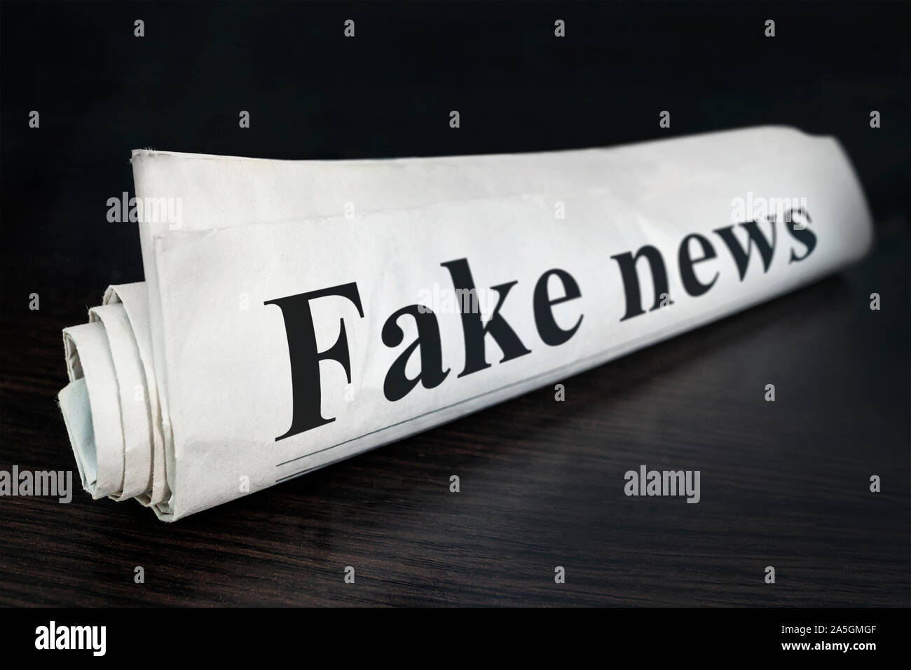 Fake News Giornale sulla scrivania in ufficio. Daily News titolo di giornale lettura notizie falso concetto di false notizie eventi headline. Arrotolate il quotidiano. Foto Stock