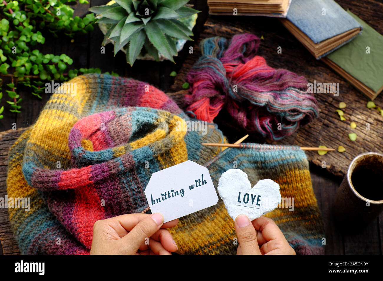 Vista superiore donna seduta al balcone di casa, tenere in mano il pezzo di carta con la scrittura di messaggio, a maglia di lana colorata sciarpa per fatti a mano significativo dono d'inverno Foto Stock