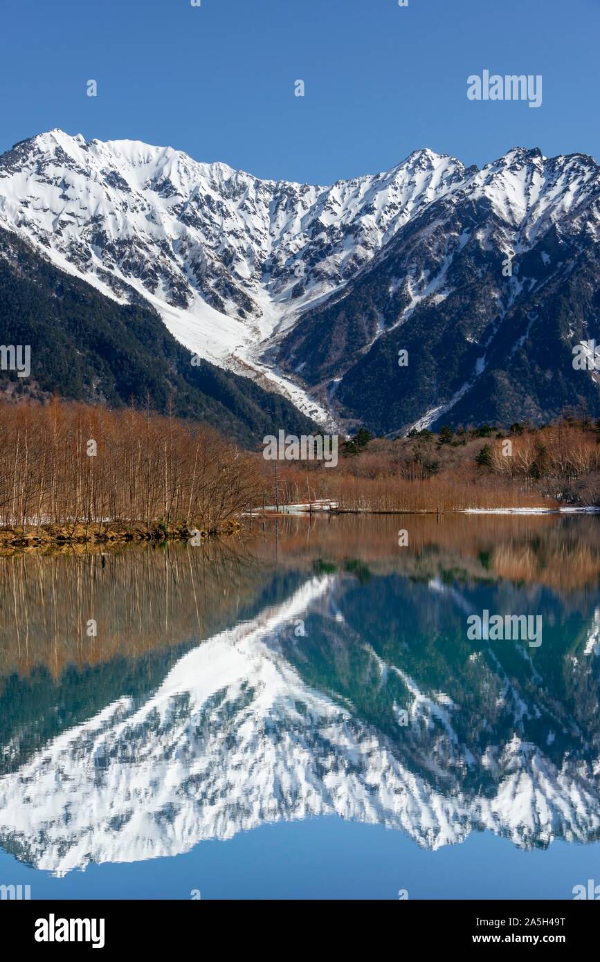 Le montagne ricoperte di neve in un lago, Alpi Giapponesi si riflette in Taisho stagno, coperta di neve Monte Hotaka sul retro, Kamikochi, Matsumoto, Nagano, Giappone Foto Stock