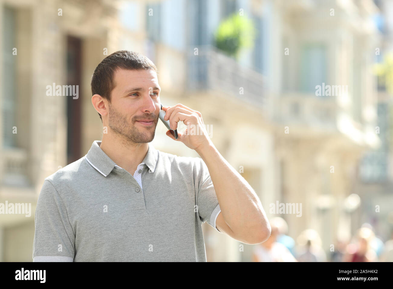 Grave adulto uomo parlando su smart phone in piedi in strada Foto Stock