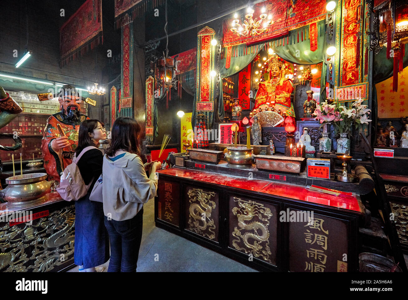 Due giovani donne pregando nel Tempio di Tin Hau complesso. Yau Ma Tei, Kowloon, Hong Kong. Foto Stock