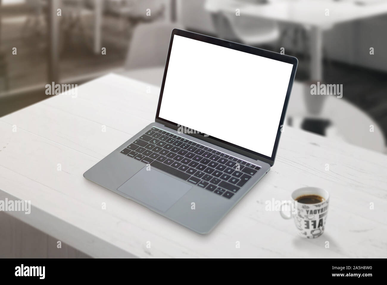 Mockup laptop sulla scrivania in ufficio con tazza di caffè accanto a. Foto Stock