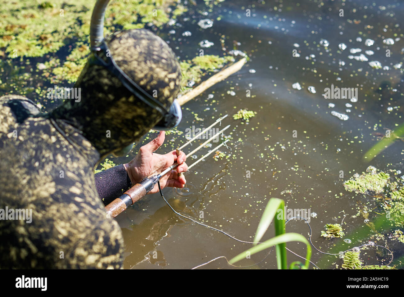Sommozzatore in muta caricamento fucile arpione per acqua caccia pesca in fiume Foto Stock