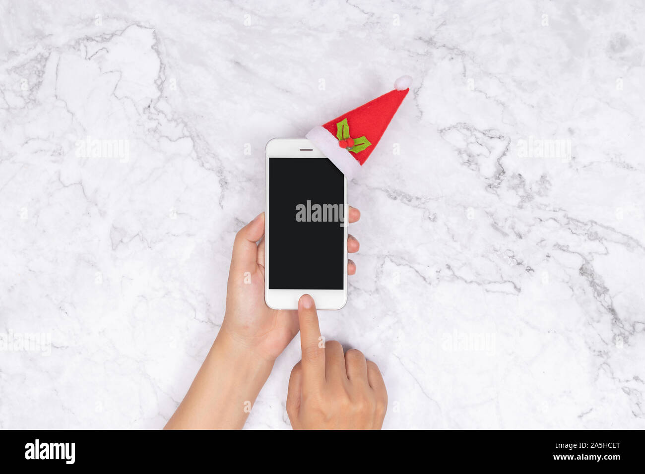 Shopping online per i regali stagionali durante il periodo natalizio. donna uso mano tocco del dito sul telefono cellulare con il pulsante schermo vuoto decorare con morbidi Foto Stock