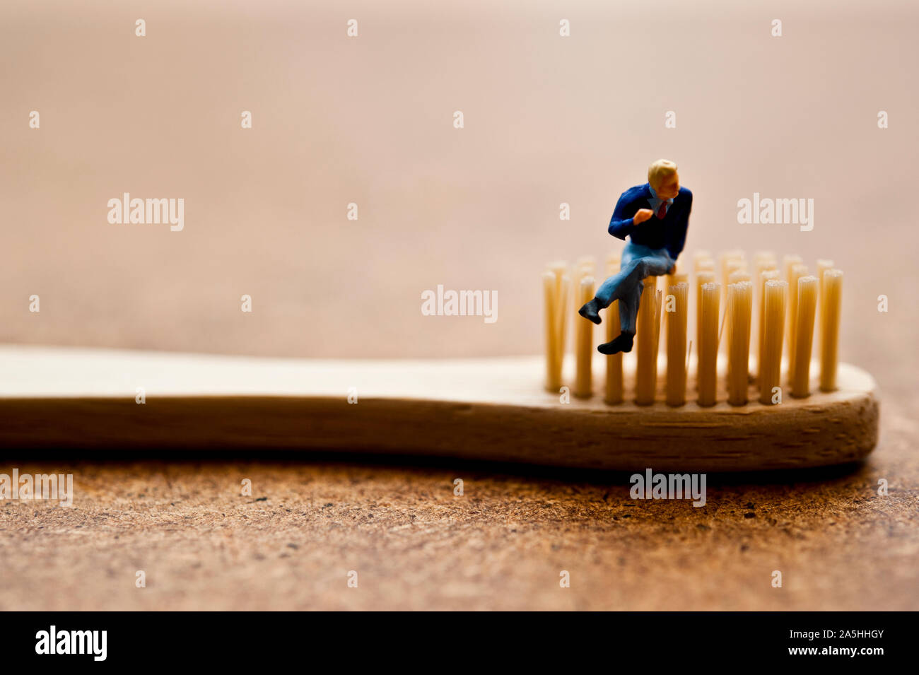 Statuetta in miniatura seduto su un spazzolino da denti di bambù - ecologica consapevole concetto dei consumatori Foto Stock