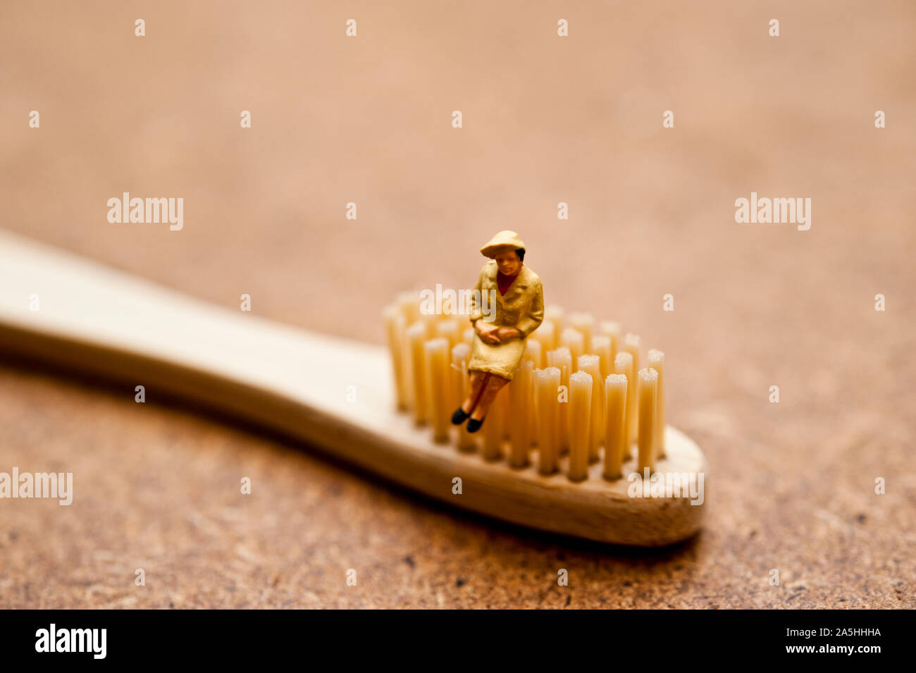 Statuetta in miniatura seduto su un spazzolino da denti di bambù - ecologica consapevole concetto dei consumatori Foto Stock