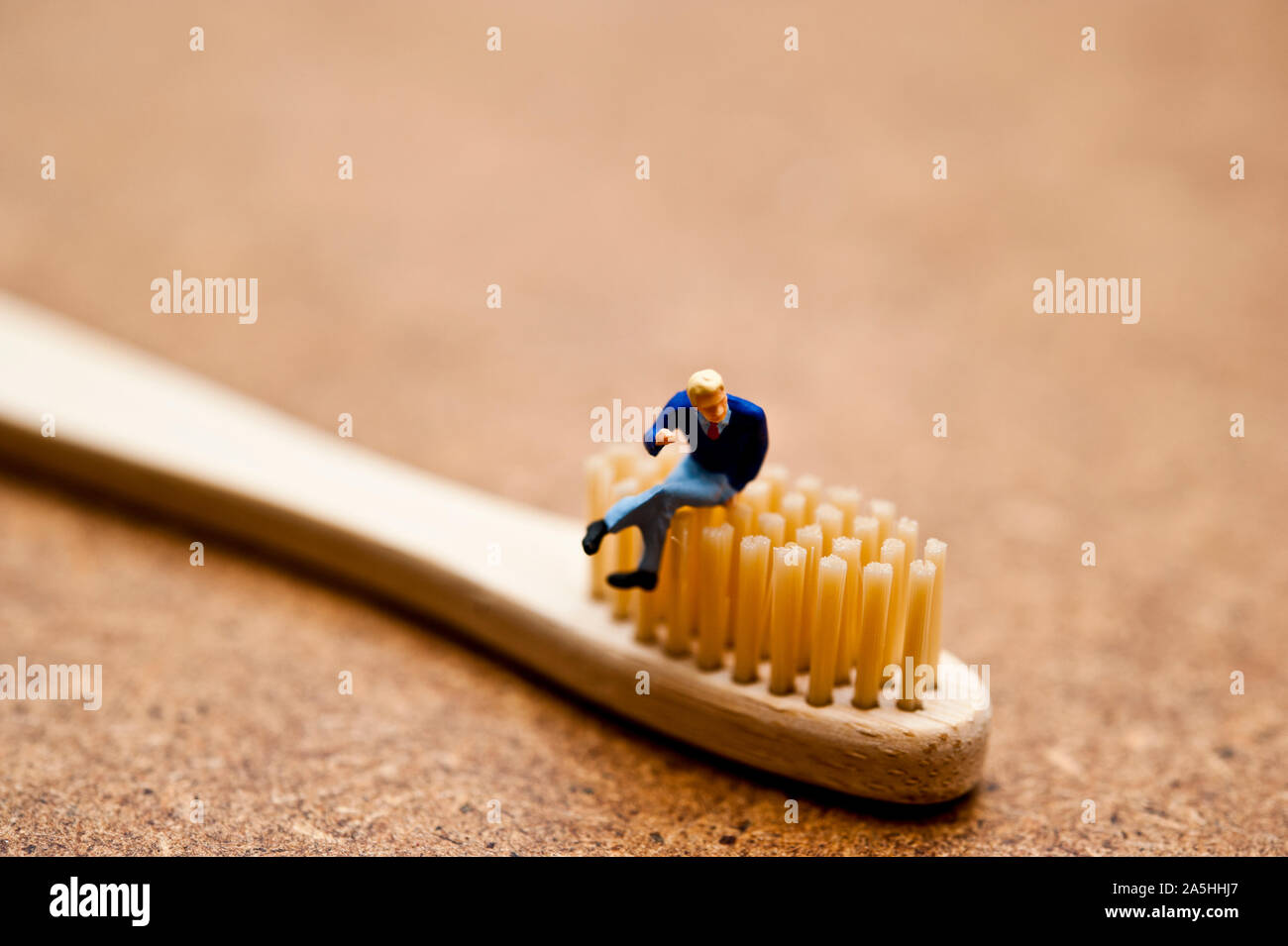 Statuetta in miniatura seduto su un spazzolino da denti di bambù - ecologica consapevole concetto dei consumatori Foto Stock