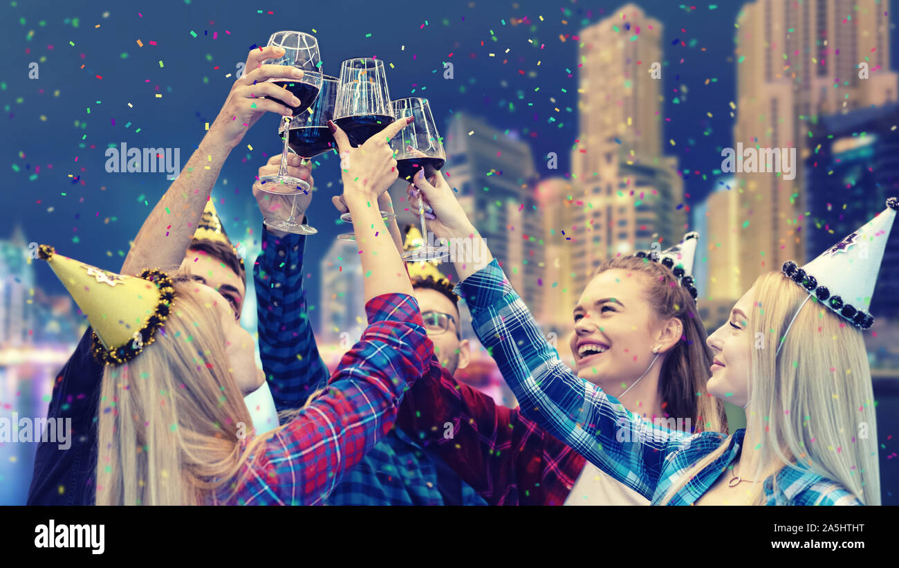 I giovani avendo divertimento bere il vino rosso di notte party sul tetto Foto Stock