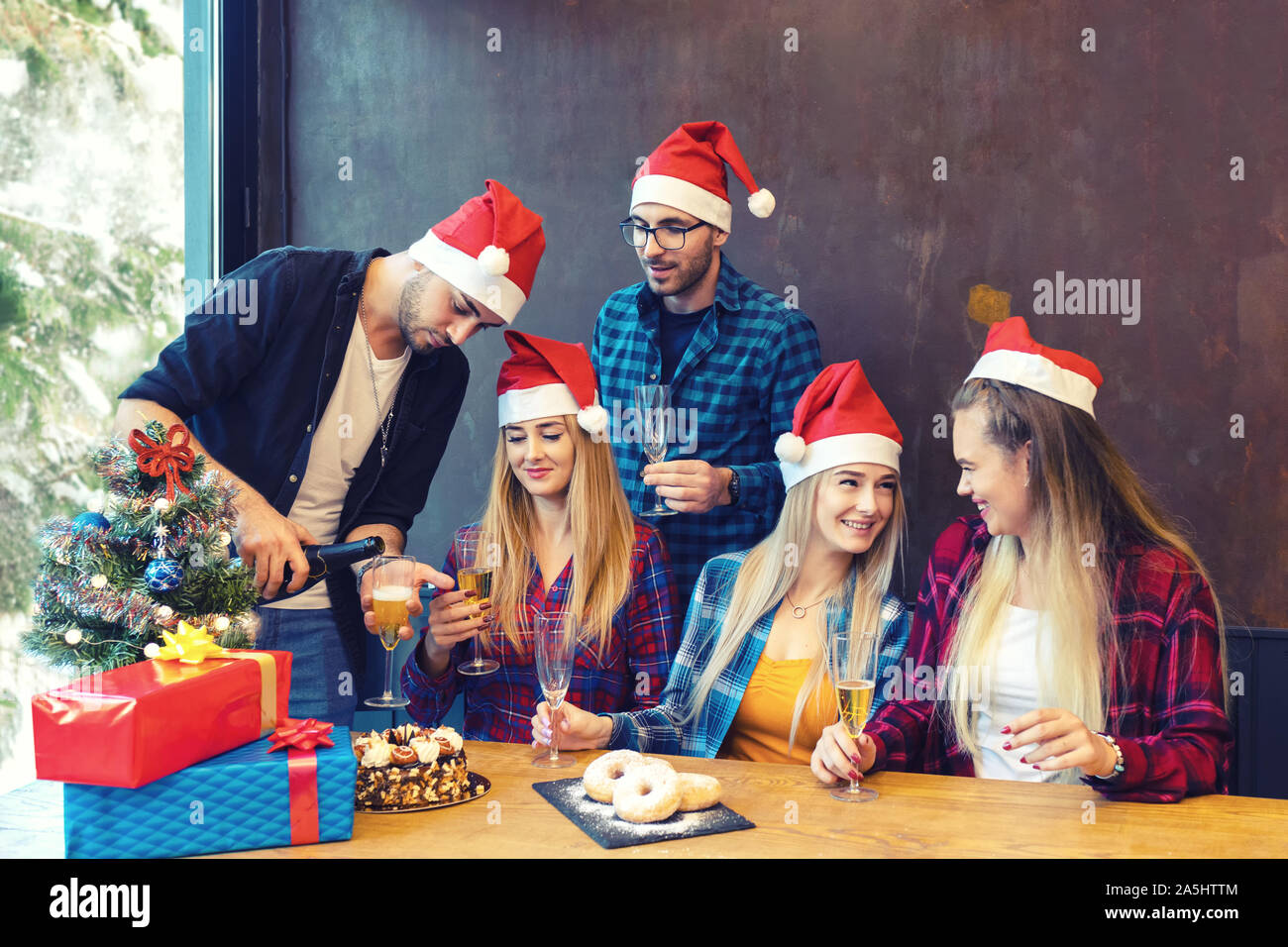 Felice gruppo di amici festeggiano il Natale bevendo champagne al partito di casa Foto Stock