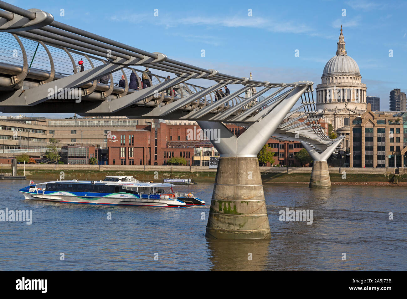 La gente camminare sopra il Ponte del Millennio attraverso il Fiume Tamigi a Londra, Inghilterra, Regno Unito. La cupola della cattedrale di San Paolo a distanza. Foto Stock