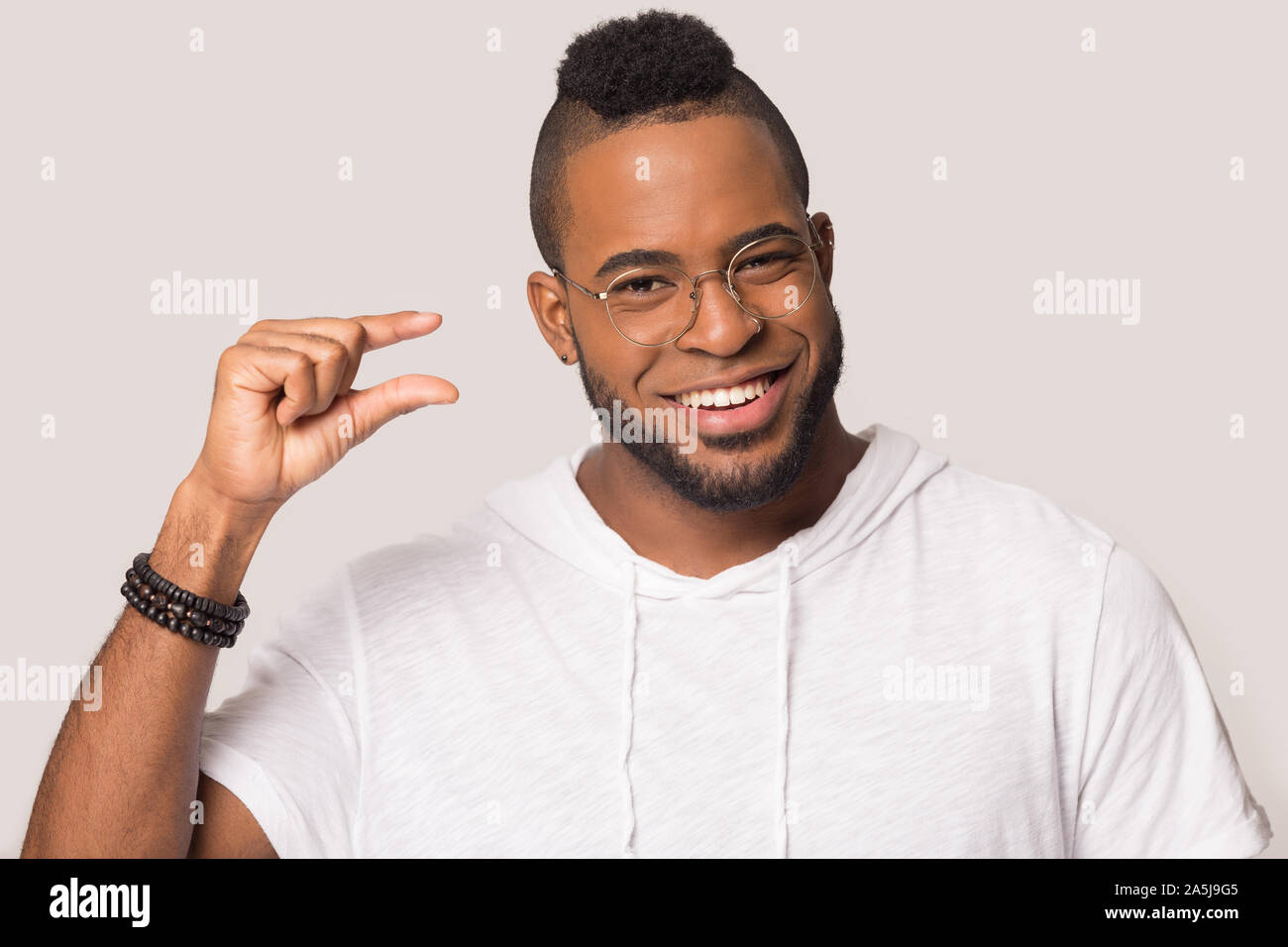 Sorridente African American uomo mostra piccole quantità con le mani Foto Stock