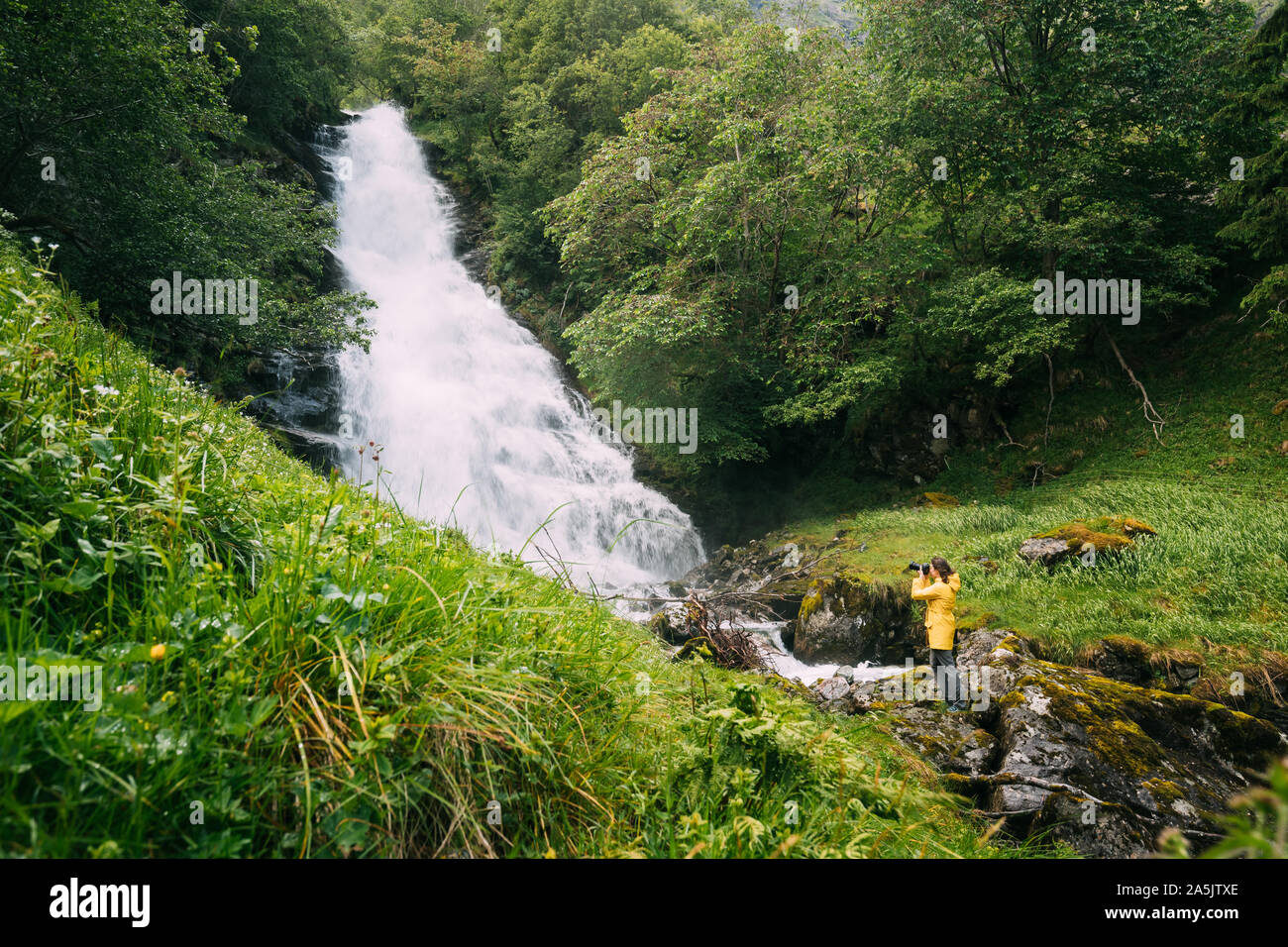 Gudvangen-Naeroyfjorden, Norvegia. Cascata Tuftofossen in primavera. Norvegese naturale punto di riferimento. Giovane donna caucasica Lady Tourist Traveler fotografo Foto Stock