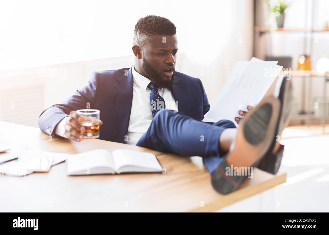 Ubriaco manager lettura report di vendita, tenendo in mano un bicchiere di Whiskey Foto Stock