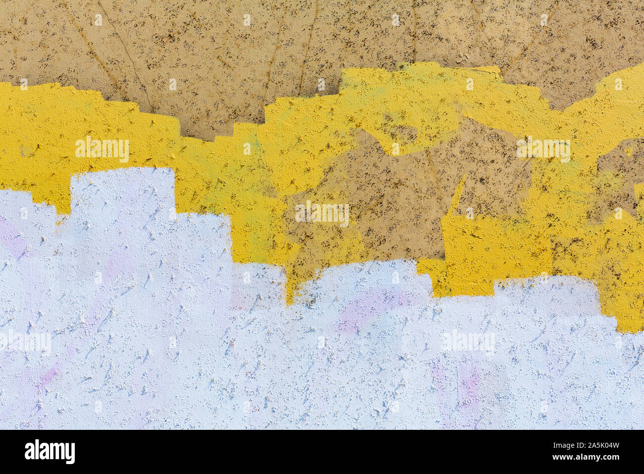 Giallo, bianco e marrone di vernice che copre i graffiti sulla parete edilizia Foto Stock
