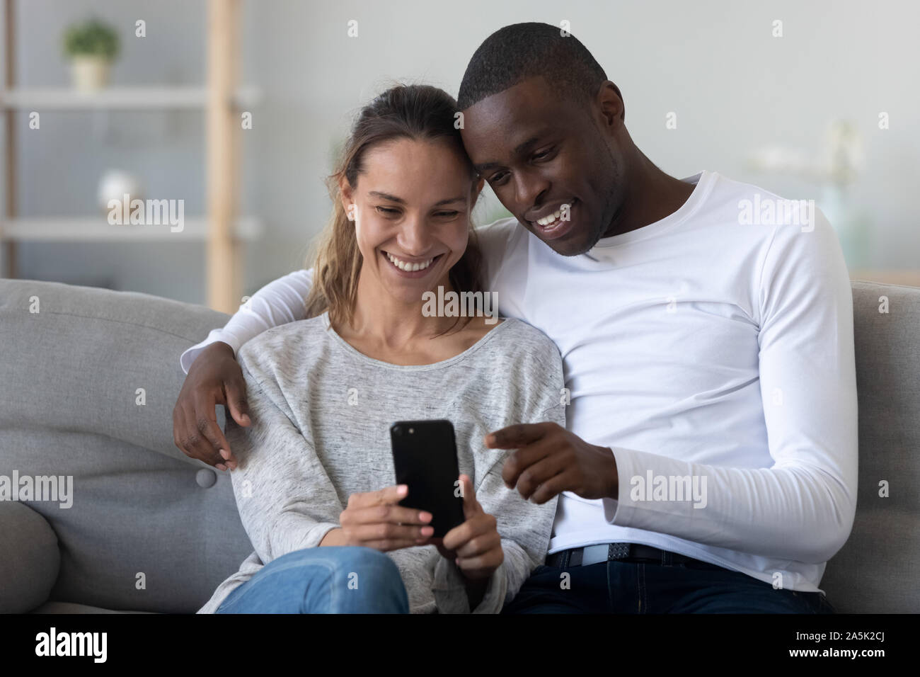 Felice coppia internazionale potrete rilassarvi sul lettino usando il cellulare insieme Foto Stock