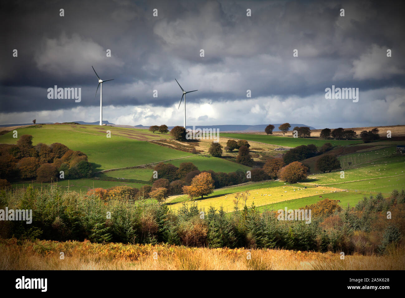 Le turbine eoliche sulla cresta della collina sopra la valle fertile con drammatica sky Foto Stock