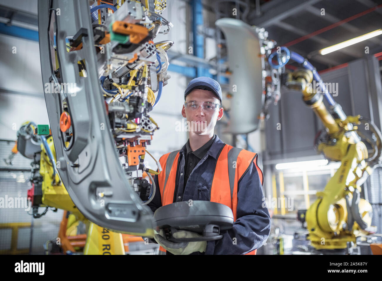 Ritratto di apprendista ingegnere programmazione di robot in fabbrica di automobili Foto Stock