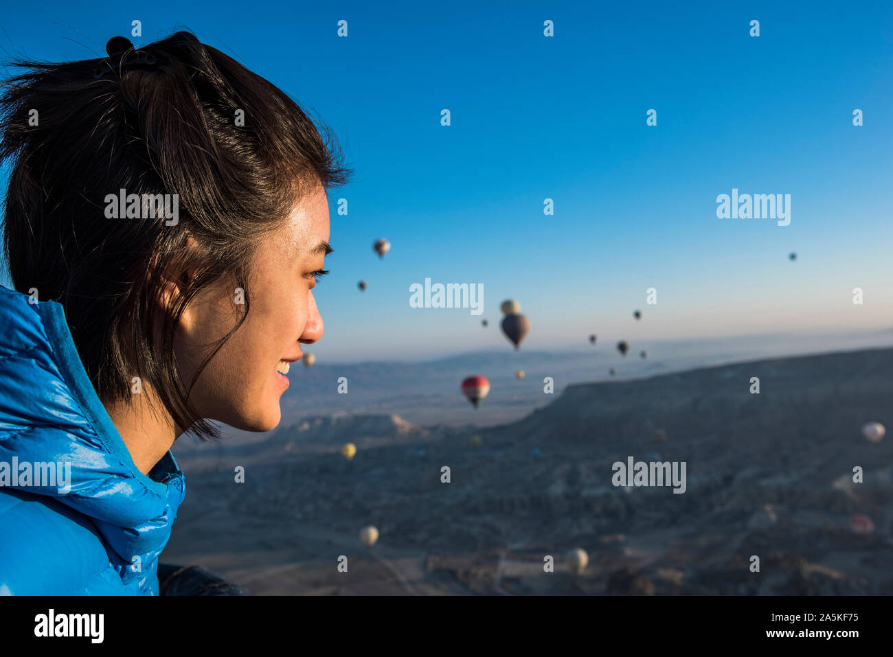La donna gode di vista, i palloni ad aria calda battenti in background, Göreme, Cappadocia, Nevsehir, Turchia Foto Stock