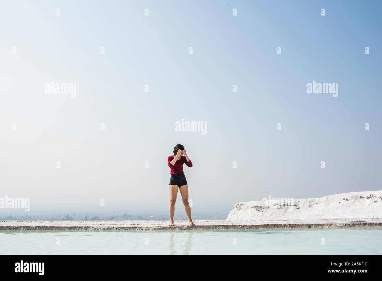 Donna che guarda verso il basso in corrispondenza di una piscina termale, Pamukkale, Denizli, Turchia Foto Stock