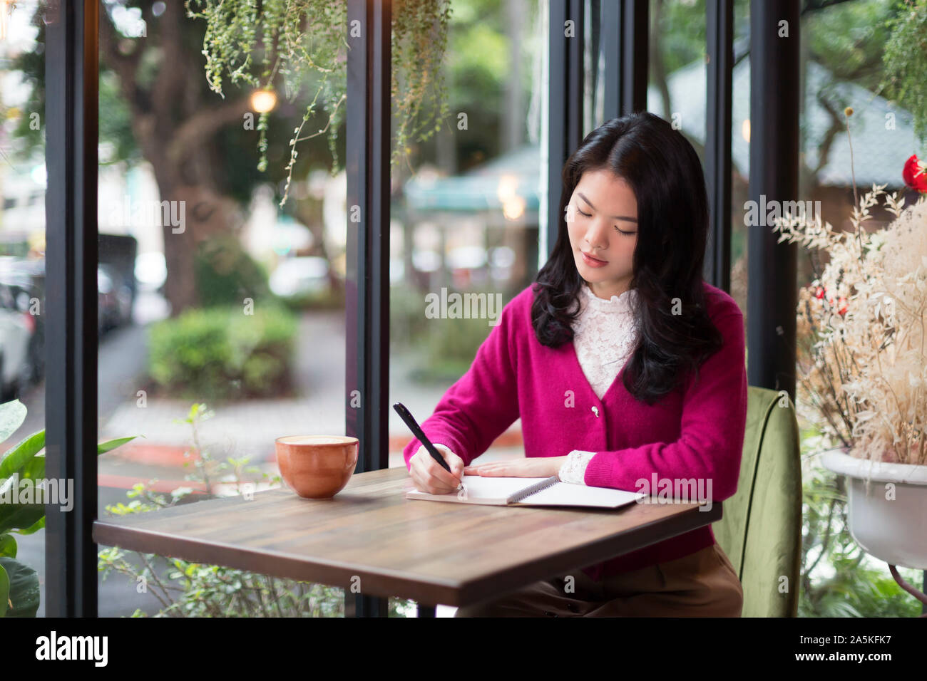 La donna nella scrittura di appunti in cafe Foto Stock