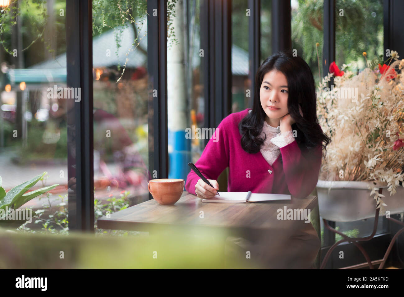 La donna nella scrittura di appunti in cafe Foto Stock