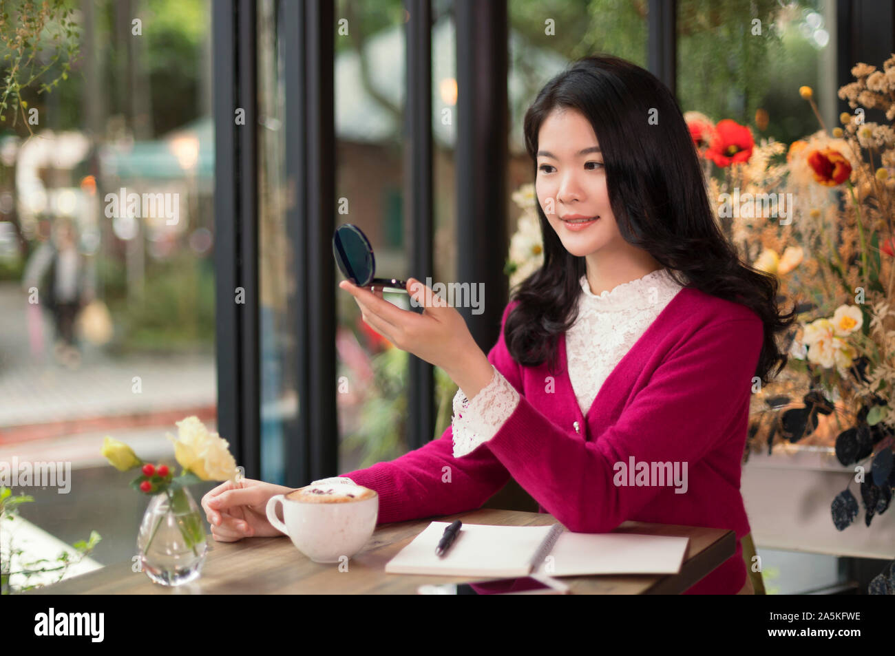 Donna che guarda in uno specchio in cafe Foto Stock