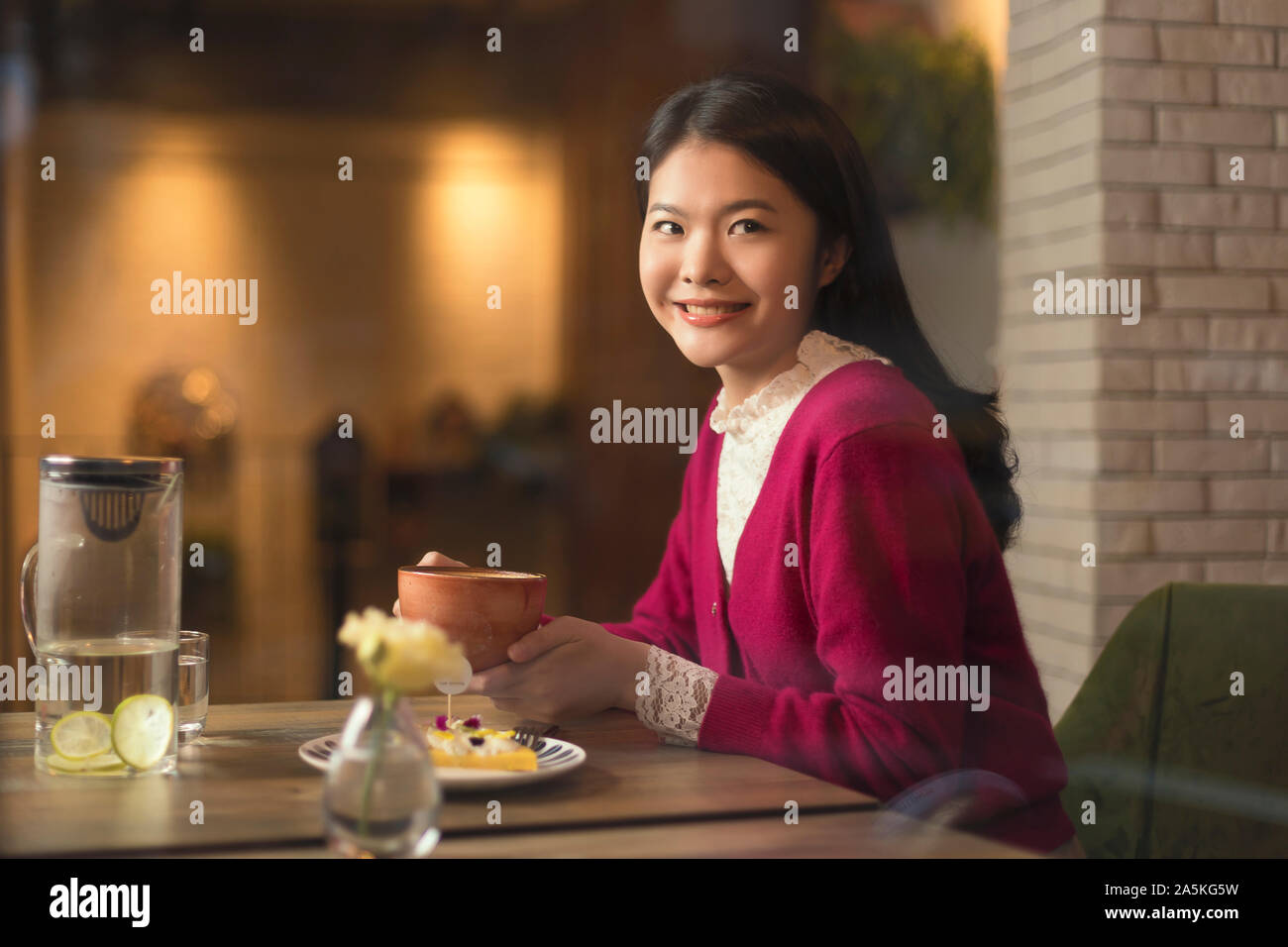 Donna con tè e una fetta di torta nel ristorante Foto Stock
