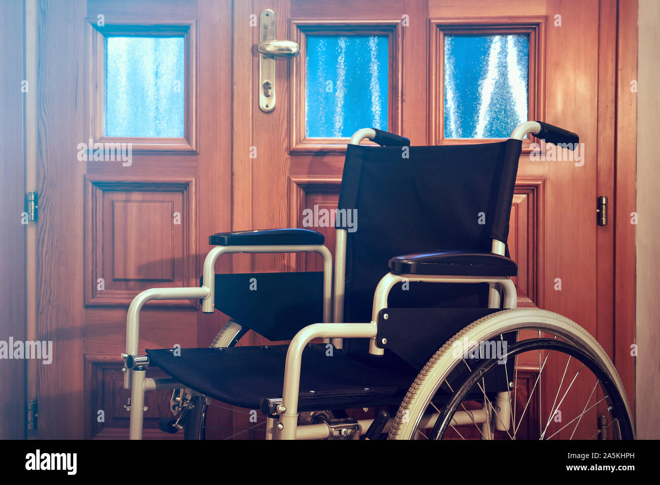 Sedia a rotelle in prossimità di una porta. Sedia vuota vicino alla porta  di una casa Foto stock - Alamy