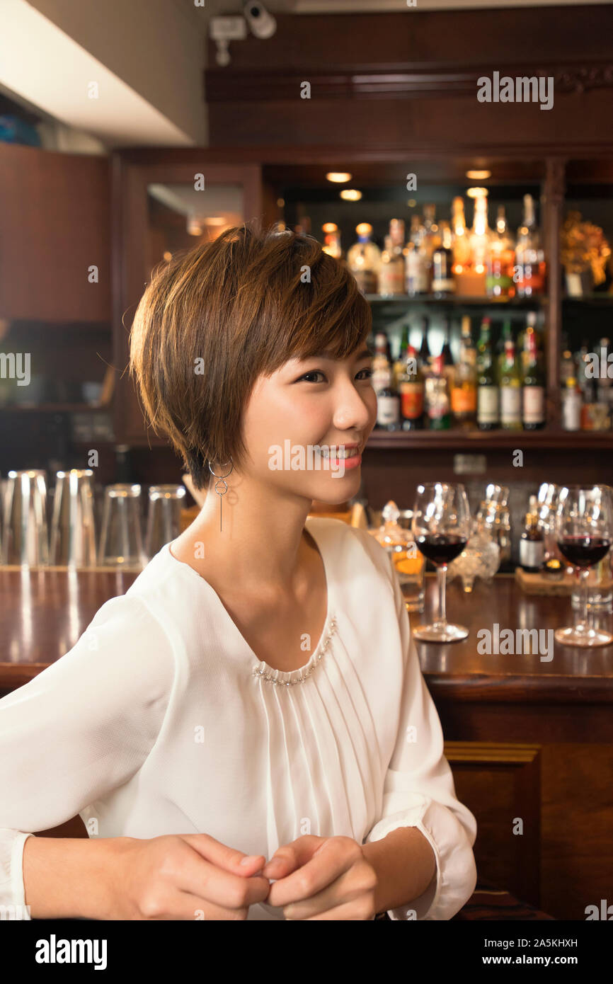 Sorridente giovane donna seduta al bancone bar Foto Stock Sorridente giovane donna seduta al bancone bar Foto Stock