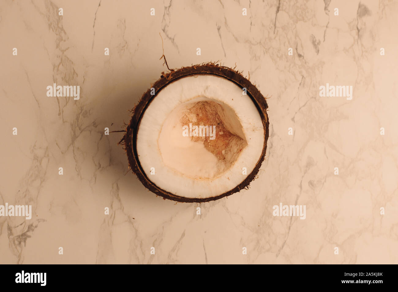 Brutto rotto organico cocco marcio su un sfondo marmo. la rottura di un dado in un guscio bianco interni di una noce di cocco, che ha cominciato a decomporsi e Foto Stock