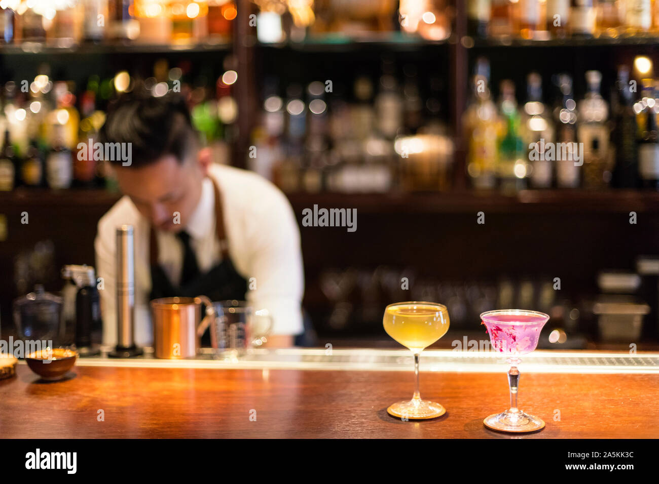 Barista e rosa e giallo cocktail sul bancone bar Foto Stock