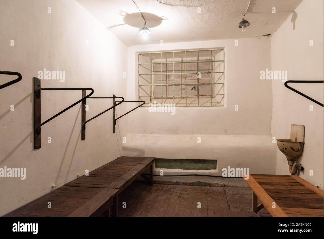Una vista interna di una cella di detenzione desolata con telai metallici e panche di legno al museo storico delle celle del KGB a Tallinn, in Estonia Foto Stock