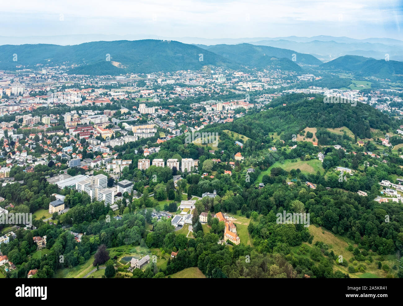 Vista aerea della città di Graz da elicottero drone con il distretto Geidorf con hill Reinerkogel su un nuvoloso giorno di estate in Austria, Europa Foto Stock