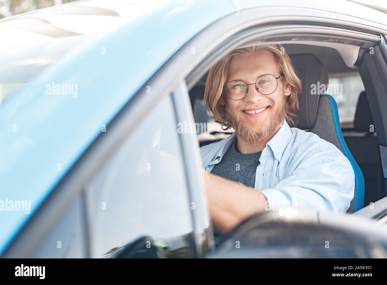 Giovane Adulto Uomo seduto in macchina e sorridente Foto Stock